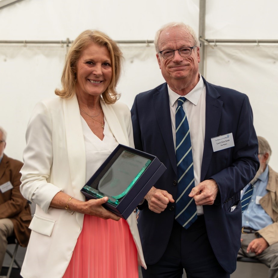 Denise Taylorson stands next to Lord Smith, holding her Volunteer of the Year Award